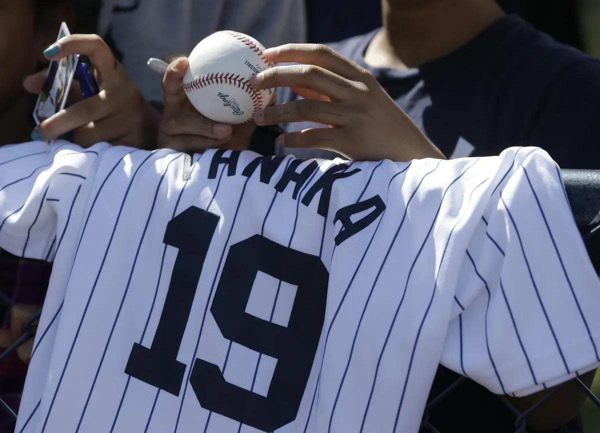 Man holding a New York Yankees jersey at a game